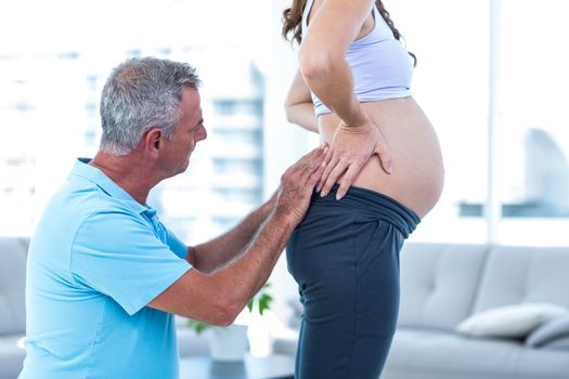 Therapist massaging pregnant woman standing at home