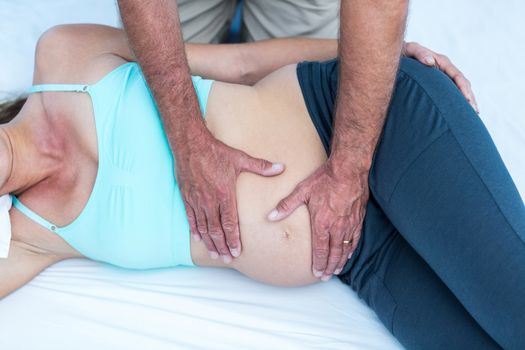 High angle view of trainer massaging pregnant woman at gym