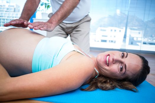 Portrait of pregnant woman smiling while getting reiki treatment in health clob