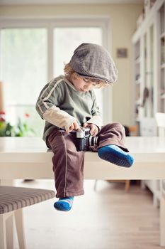 Small boy with a cap inspecting a retro camera