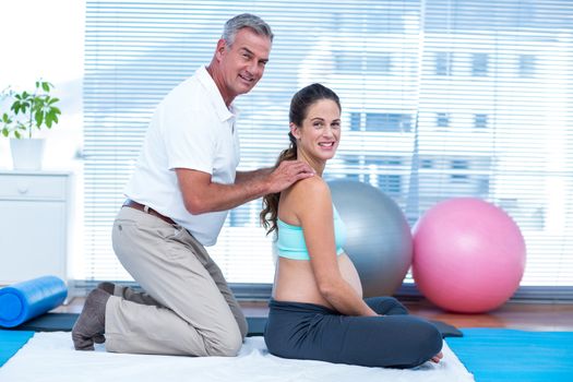 Portrait of gym trainer massaging pregnant woman 