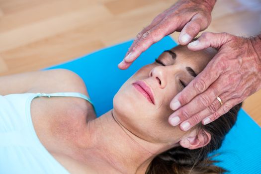 Relaxed woman getting reiki treatment in health club