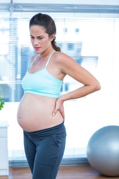 Thoughtful pregnant woman standing in yoga class