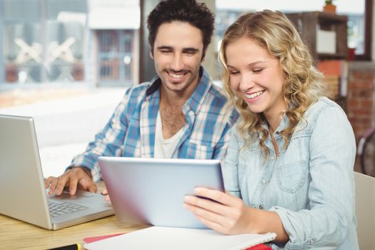 Colleagues smiling and looking at digital tablet in office 