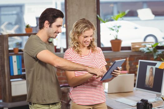 Business people looking at digital tablet while standing in office 