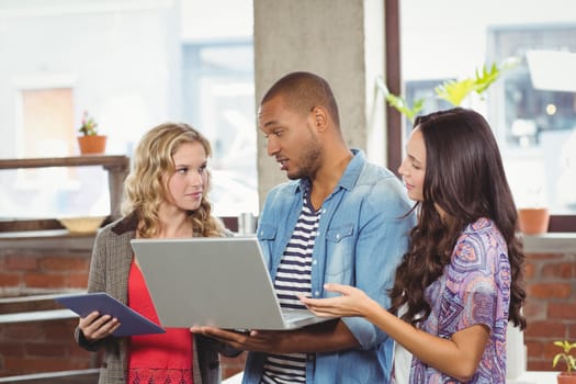 Business people discussing while holding technologies in creative office