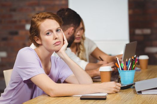 Portrait of businesswoman with hand on chin sitting in creative office 