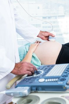 Male doctor doing ultrasound on pregnant woman in clinic