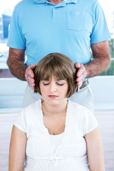 Therapist performing reiki over woman at health center