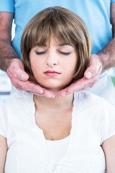 Close-up of calm woman receiving reiki from male therapist at health club
