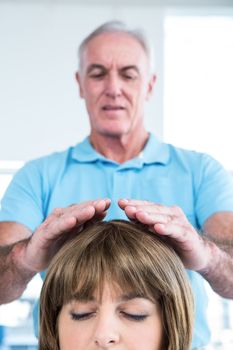 Male therapist performing reiki over woman at health center