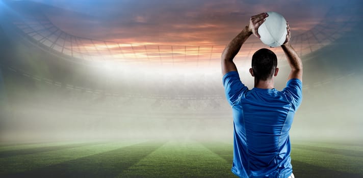 Rear view of rugby player throwing ball against rugby pitch