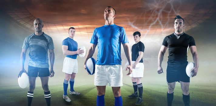 Portrait of sportsman holding rugby ball while standing against rugby pitch