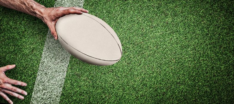 Cropped image of a man holding rugby ball against pitch with line