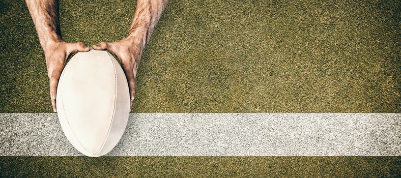 Man holding rugby ball against pitch with line