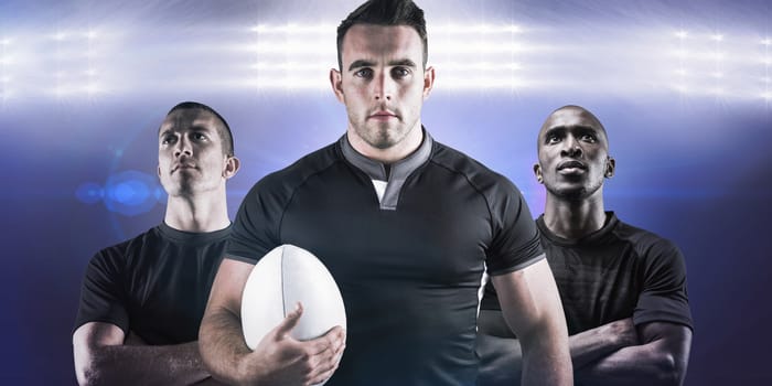 Tough rugby player holding ball against spotlights