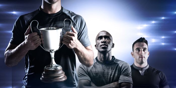 Victorious rugby player holding trophy against spotlight