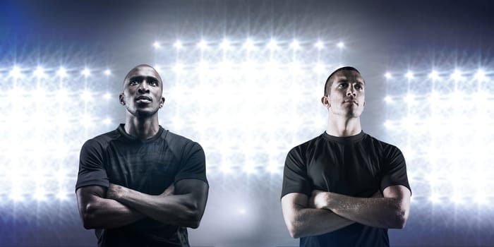 Thoughtful rugby player with arms crossed against spotlight