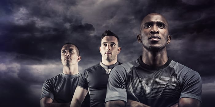 Thoughtful athlete standing with arms crossed against blue sky