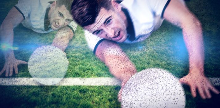 Man holding rugby ball while lying down against rugby pitch