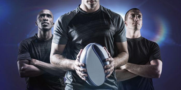 Thoughtful rugby player holding ball against spotlights