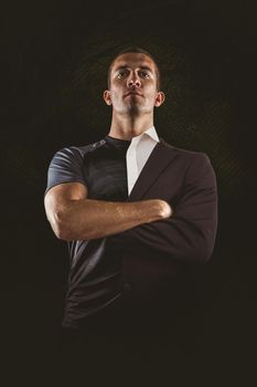 Confident rugby player with arms crossed against half a suit
