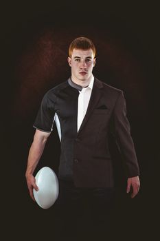 Rugby player holding a rugby ball against half a suit