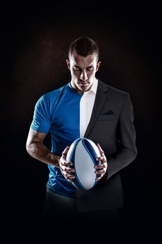 Rugby player holding ball against half a suit