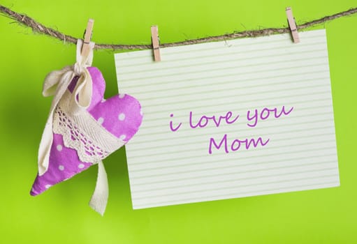 message card with the inscription I love you Mom and handmade heart of the cloth with polka dots on a rope with clothespins, greeting concept 