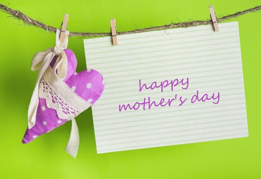 Mothers day message card with the inscription Happy Mother's Day and handmade heart of the cloth with polka dots on a rope with clothespins, greeting concept 