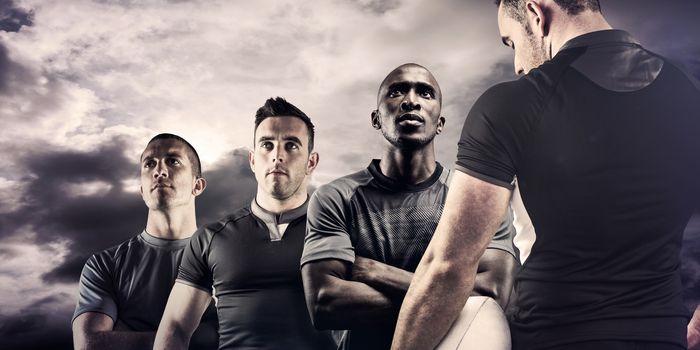 Tough rugby player holding ball against blue sky with white clouds