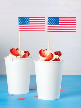 Two dessert of strawberries and whipped cream in a paper cup with American flags, greeting concept for Independence Day of America, the day of the American flag