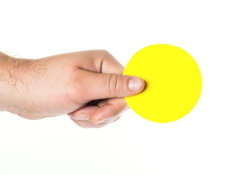 man's hand holding a round yellow tablet, plate for text or inscriptions