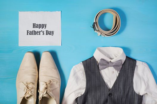 Greeting card for Dad's Day, a white shirt,  men's shoes, gray vest and bow tie, a belt and a sheet of paper with text  Happy Father's Day, concept