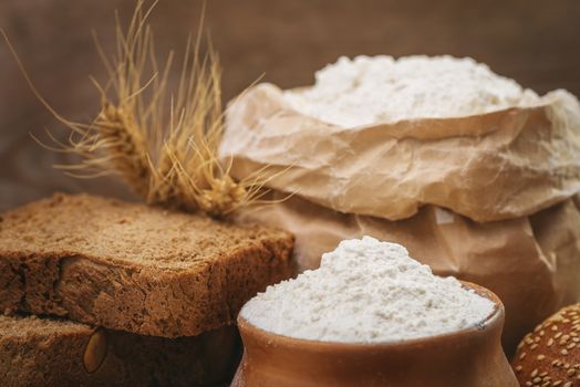 Wheat flour, sliced bread, wheat ears on an old wooden background