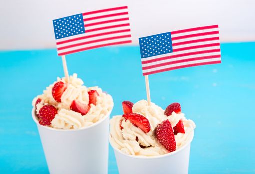 Two dessert of strawberries and whipped cream in a paper cup with American flags, greeting concept for Independence Day of America, the day of the American flag