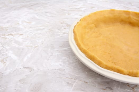 Close-up of pie dish lined with pastry, with copy space on kitchen worktop