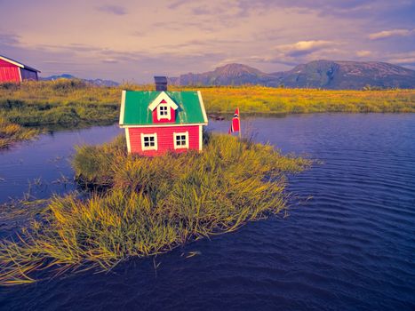 Romantic miniature scandinavian red house on tiny islet