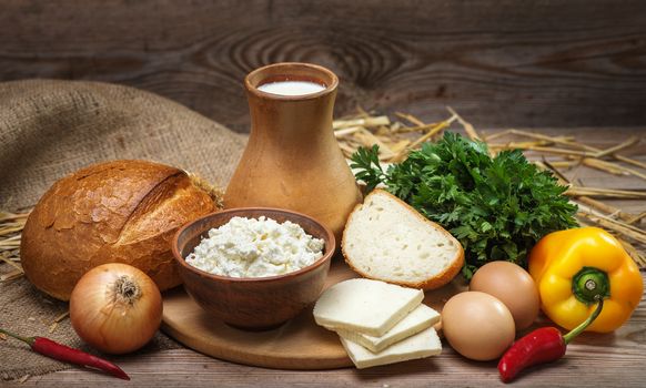 Farmers rustic natural organic foods, balanced diet, cooking, culinary, food concept, dairy products, bread, cheese, cottage cheese, eggs, onions, milk on the old wooden background