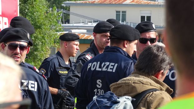 AUSTRIA, Salzburg: Police officials stand guard as scores line up at the border control in Salzburg, Austria on September 22, 2015 amid an ongoing refugee crisis, which has seen thousands flee from Syria and other war-torn countries for safety in Europe.