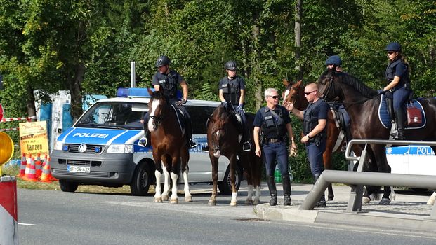 AUSTRIA, Salzburg: Police officials stand guard on horseback as scores line up at the border control in Salzburg, Austria on September 22, 2015 amid an ongoing refugee crisis, which has seen thousands flee from Syria and other war-torn countries for safety in Europe.