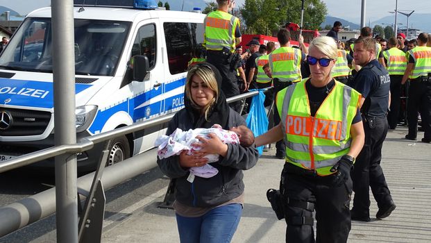 AUSTRIA, Salzburg: A police woman escorts a woman and her baby at the border control in Salzburg, Austria on September 22, 2015 amid an ongoing refugee crisis, which has seen thousands flee from Syria and other war-torn countries for safety in Europe.