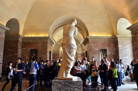 Paris, France - May 13, 2015: Tourists visit The Venus de Milo statue at the Louvre Museum in Paris. The Venus de Milo statue it's one of most important statue of the world.