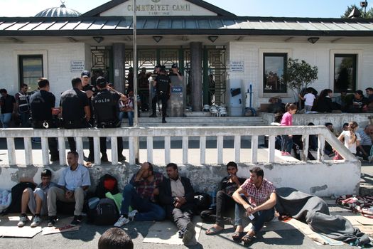 TURKEY, Istanbul: Refugees sit and wait near the Esenler Bus Terminal in Istanbul, Turkey on September 19, 2015 after the government ordered that bus tickets not be sold to them. They are waiting for the government to reverse the decision so they can travel to the Turkish border town of Edirne to continue their journey into Europe