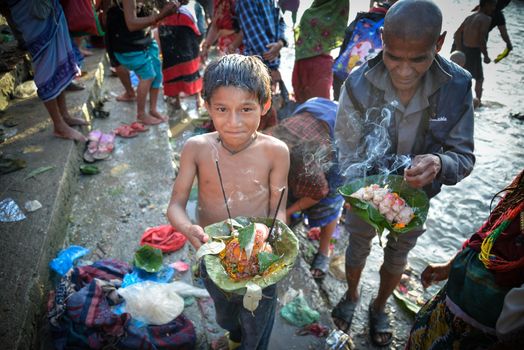 NEPAL, Nuwakot: Santosh Shrestha, a 10 year-old boy from Okharpauwa, Nuwakot District performs a religious ritual at Bagamti River Bank during Father's Day, on September 13, 2015.	Santosh's father passed away when he was six months old, and this was his fifth time performing the religious ritual at Gokarna, along with his grandfather, grandmother and his mother. He lives in poverty on a rubbish dump with his family, and is not able to go to school. 