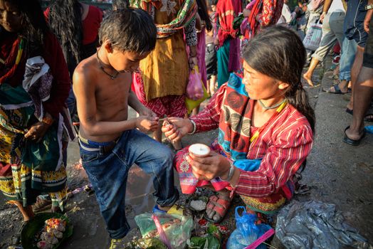 NEPAL, Nuwakot: Santosh Shrestha, a 10 year-old boy from Okharpauwa, Nuwakot District performs a religious ritual at Bagamti River Bank during Father's Day, on September 13, 2015.	Santosh's father passed away when he was six months old, and this was his fifth time performing the religious ritual at Gokarna, along with his grandfather, grandmother and his mother. He lives in poverty on a rubbish dump with his family, and is not able to go to school. 