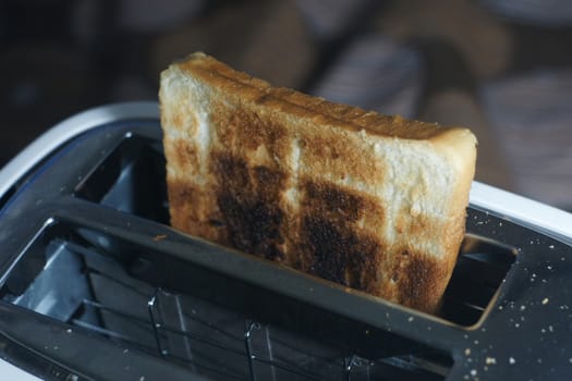 White dirty toaster and burned toast (selective focus, dark tone)