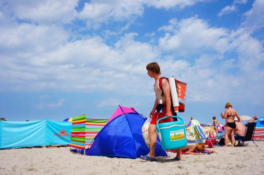 SIANOZETY, POLAND - JULY 22, 2015: Man carrying food and walking on a beach