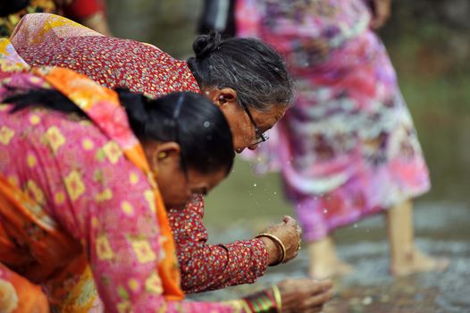 NEPAL, Lalitpur: Women splash water on their face as they celebrate Bunga Dyah Jatra, more commonly known in Nepal as Rato Machhendranath, on September 23, 2015 in Laltipur, Nepal. The festival is celebrated by pulling a chariot through the Nakhu River.   Rato Machhendranathis is known as the god of rain to both Hindu and Buddhist worshippers, who hope the celebration will bring enough rain to prevent droughts during the rice plantation season.  