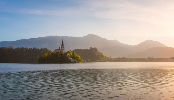 Little Island with Catholic Church in Bled Lake, Slovenia  at Sunrise with Castle and Mountains in Background